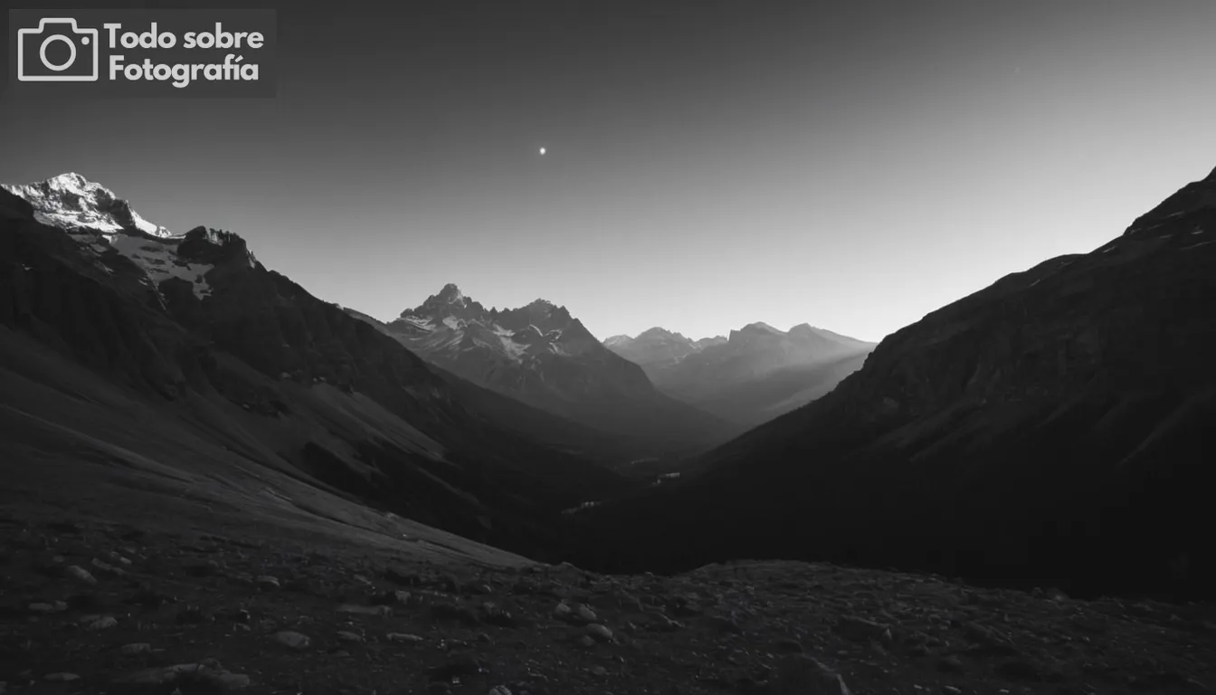 Vista panorámica, majestuoso paisaje de montaña silueta, cielo expansivo, efectos de iluminación suave, estética negra y blanca, contrastes dramáticos, Ansel Adams estilo icónico, composición minimalista, sombras profundas y momentos destacados, escena natural intemporal